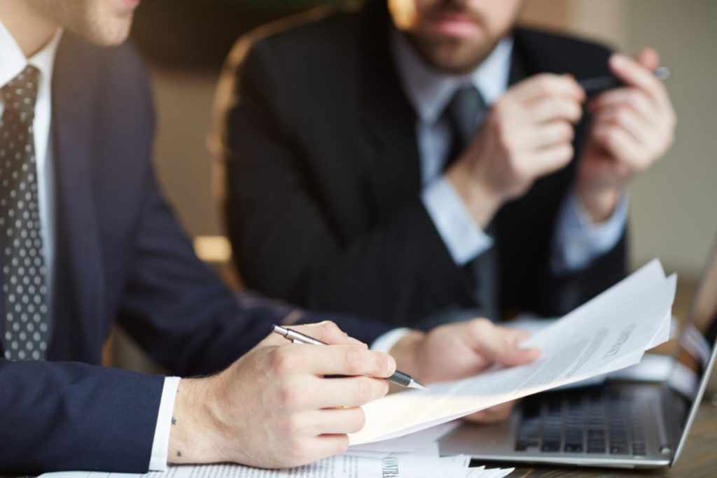 Advogados sentados analisando documentos, representando a assessoria jurídica.