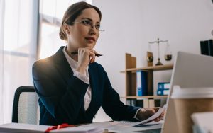 Executiva pensativa olhando para tela de notebook.