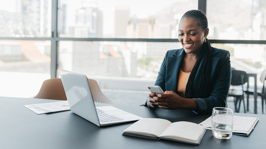 Executiva sorridente em escritório usando o celular
