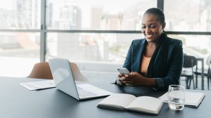 Executiva sorridente em escritório usando o celular