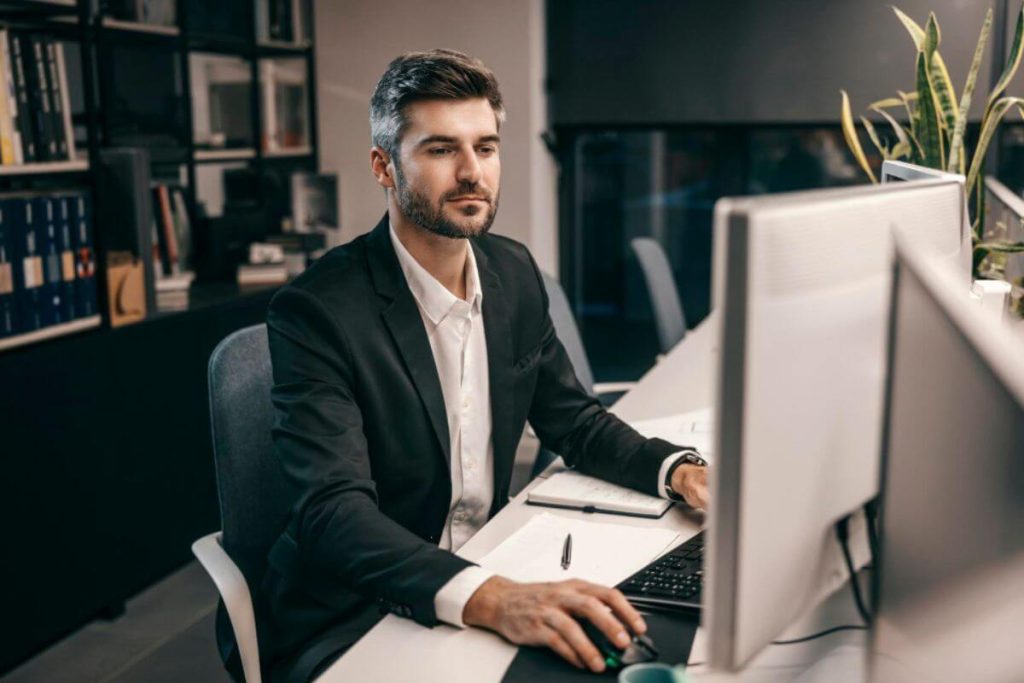 Advogado em um escritório de advocacia mexendo no computador, representando a implementação de software jurídico.