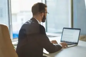 Advogado digitando um documento no notebook, representando qual melhor software jurídico.