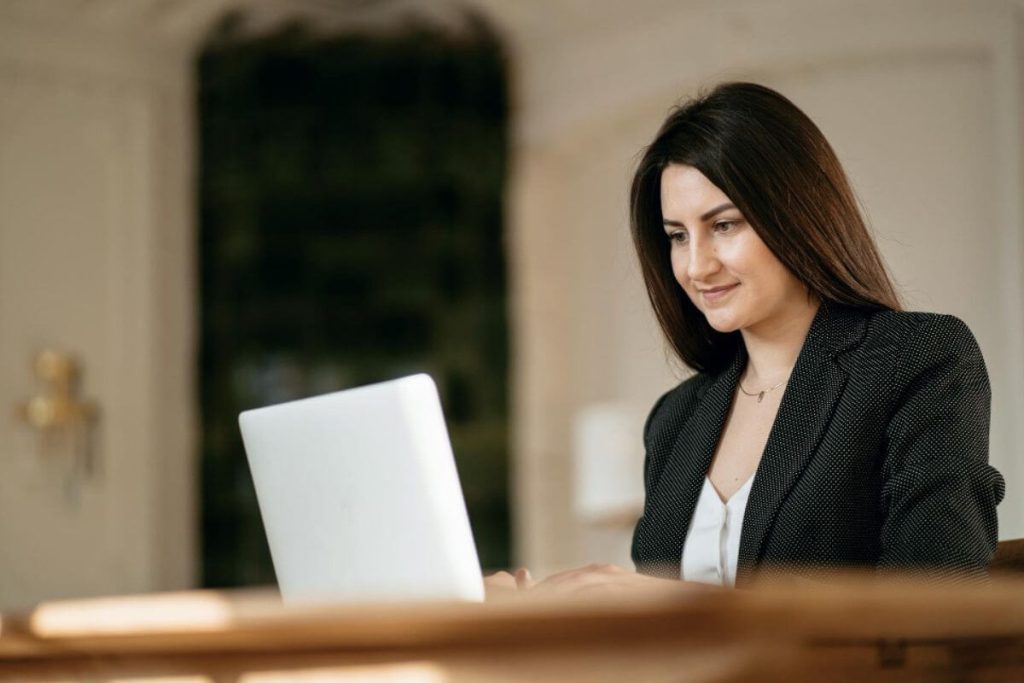 Advogada mexendo no notebook em uma sala ampla, representando o software jurídico com inteligência artificial.