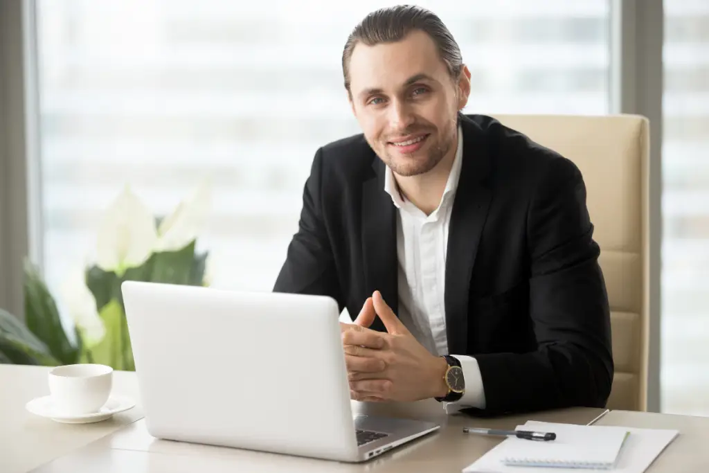 Advogado sorridente com um notebook aberto à sua frente, representando uma gestão de serviços jurídicos.