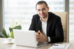 Advogado sorridente com um notebook aberto à sua frente, representando uma gestão de serviços jurídicos.