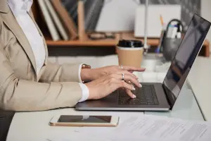 Mãos femininas estão digitando sobre o teclado de um notebook, ilustrando um artigo do GOJUR sobre como aumentar a produtividade.